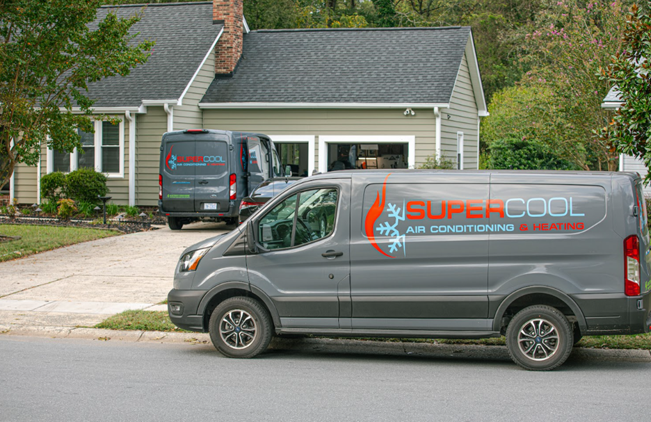 Two electric vans with Super Cool branding parked in front of a house.