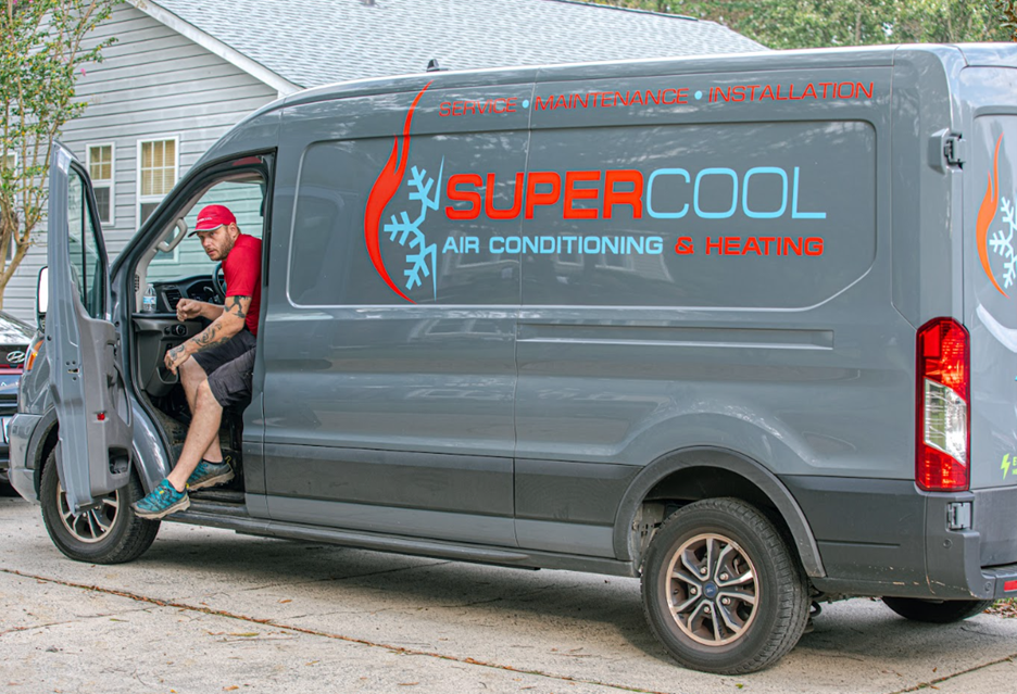 An electric van with Super Cool branding is parked in front of a house with a technician exiting the vehicle.